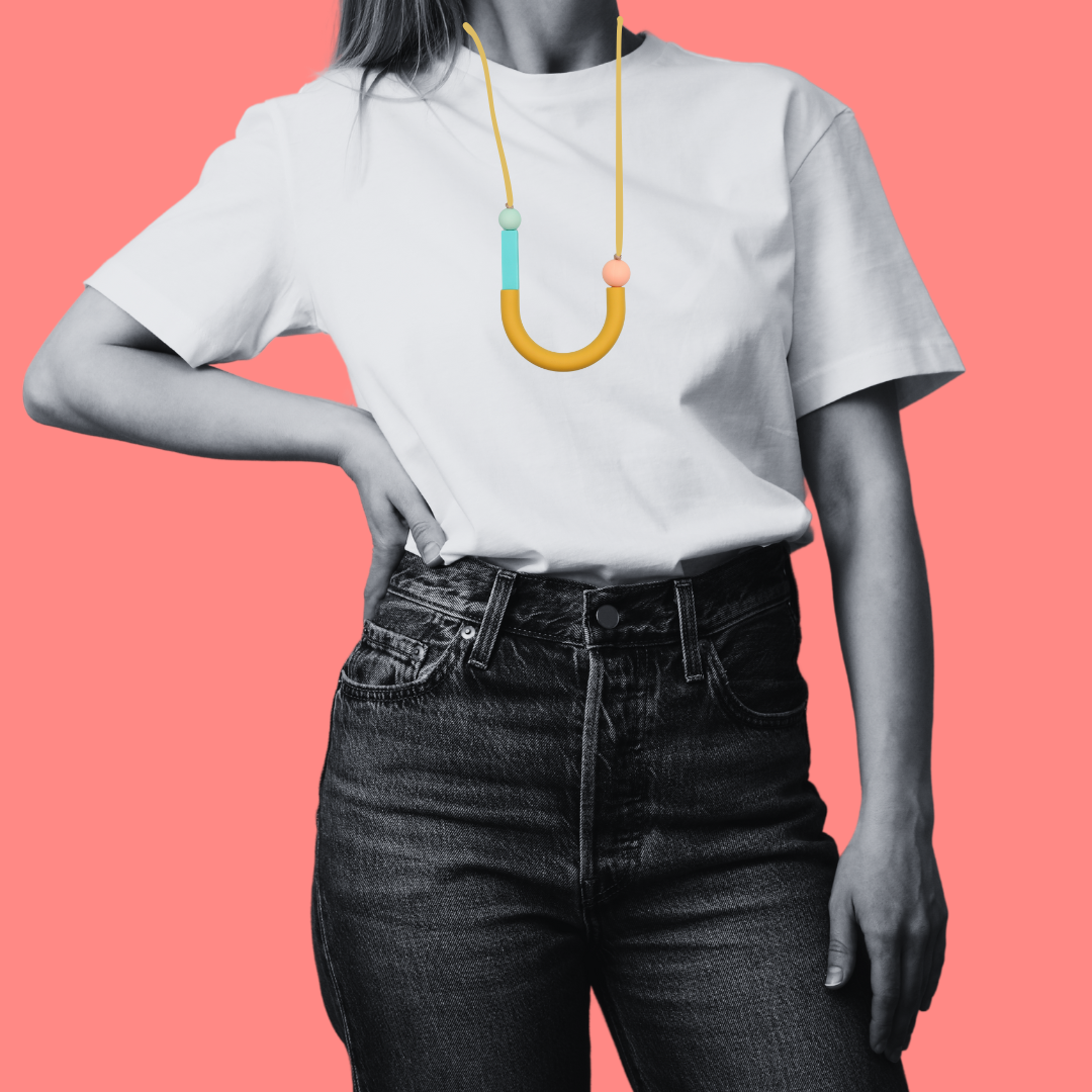 Woman in white t shirt on pink background wearing asymmetrical u shaped silicone sensory seekers necklace.