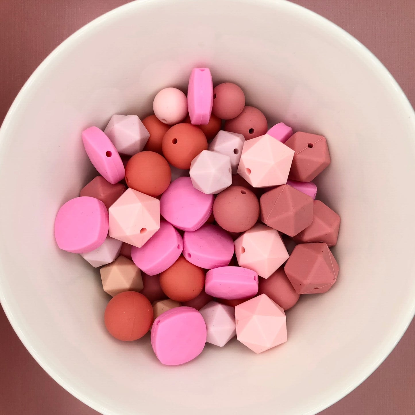 Variety pack of 50+ mixed size and shape silicone beads in various pink hues.