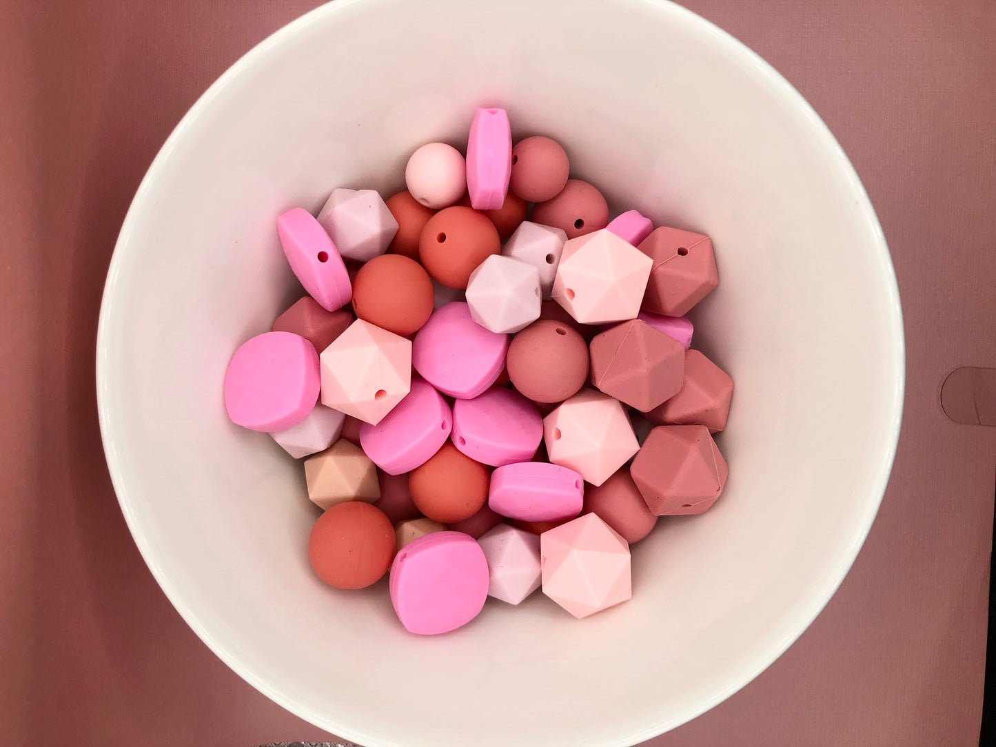 Variety pack of 50+ mixed size and shape silicone beads in various pink hues.