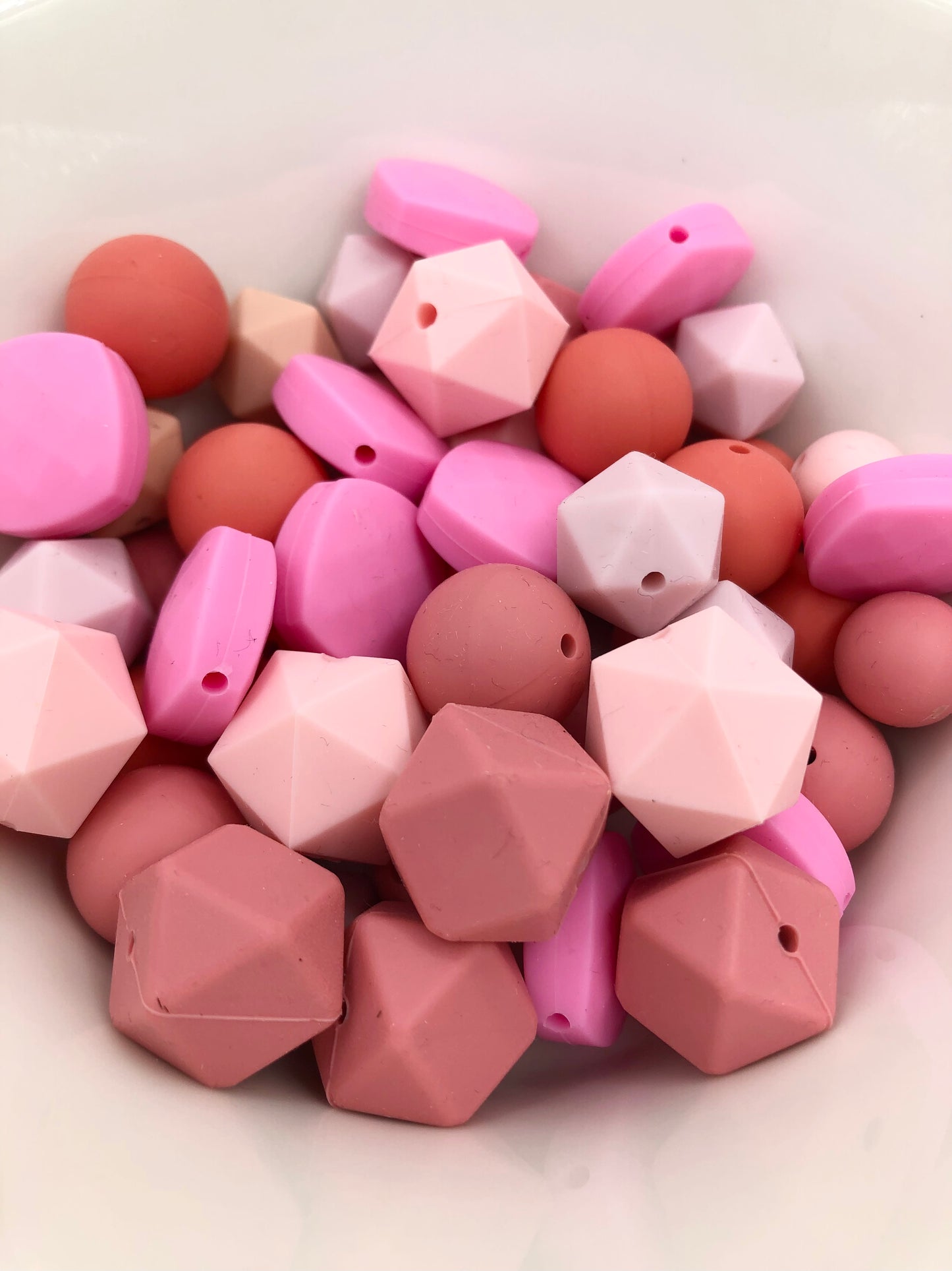 Variety pack of 50+ mixed size and shape silicone beads in various pink hues.
