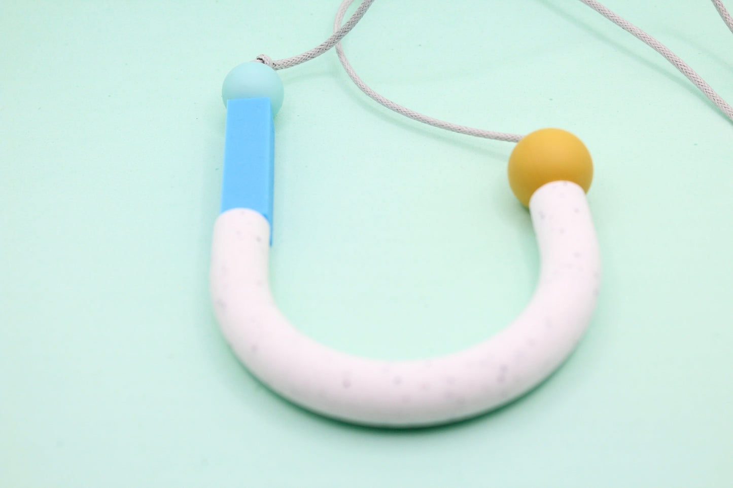 U-shaped silicone necklace for sensory and teething use worn by adults.
